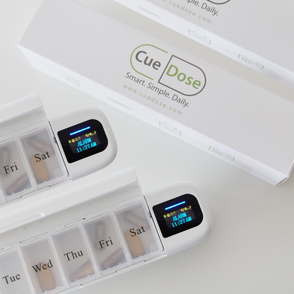 Digital pill box organiser on white surface showing alarm to take medication